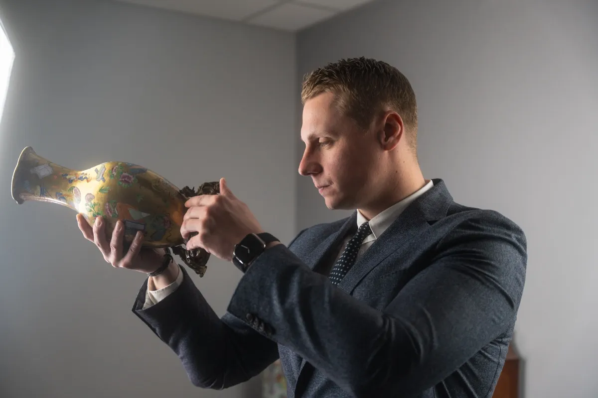 Florian, expert de l'équipe, examine un vase chinois de Canton à monture en bronze