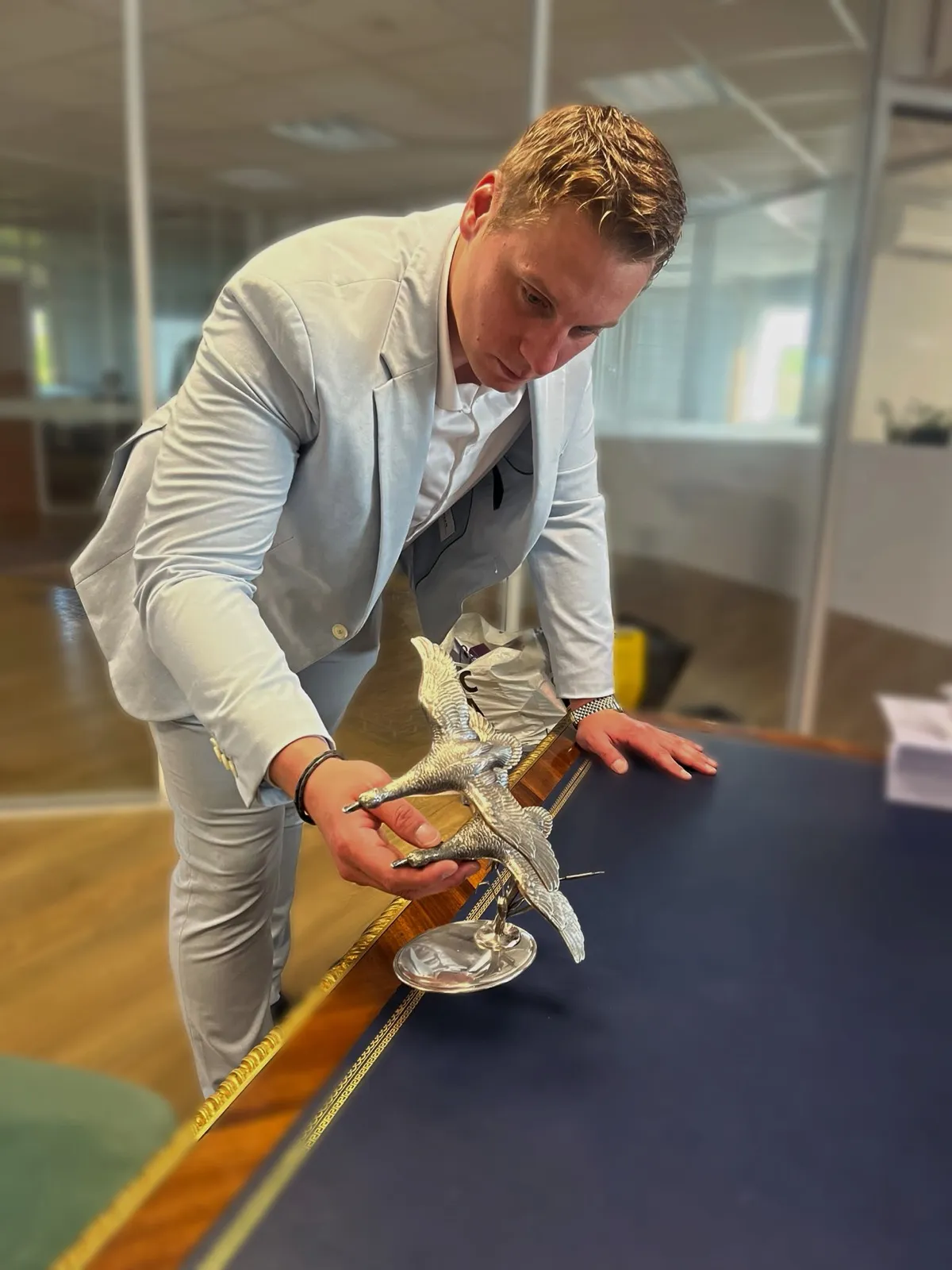 Florian, expert de l'équipe, examine une sculpture d'oiseaux en métal argenté