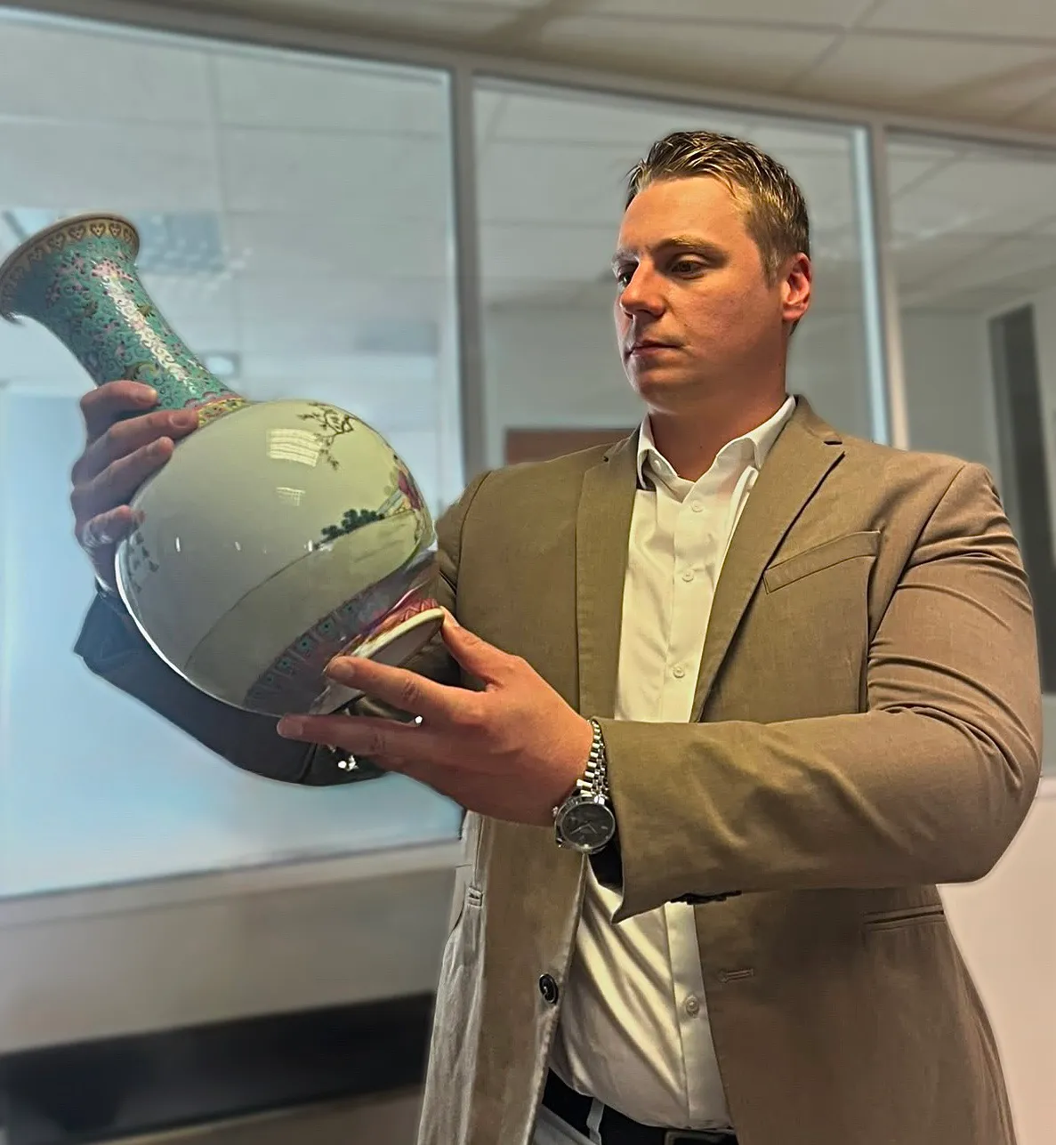 Florian, expert de l'équipe, examine un vase chinois en porcelaine famille rose pour l'estimer